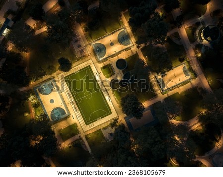 Sport courts at a park in aerial view. Evening photo about foutball, basketball courts and ping pong tables. Illuminated recreation park.