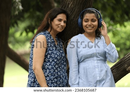 Young daughter listening music with her daughter while standing on park.