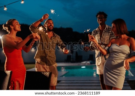 Group of multiethnic friends enjoying their party next to the pool, dancing and using sprinkles after dinner Royalty-Free Stock Photo #2368111189