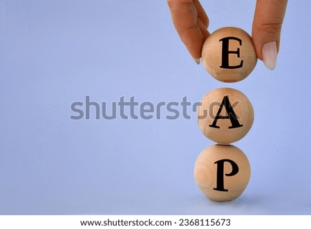 A woman's hand holds a wooden ball with the abbreviation EAP(Employee Assistance Program). Business concept Royalty-Free Stock Photo #2368115673