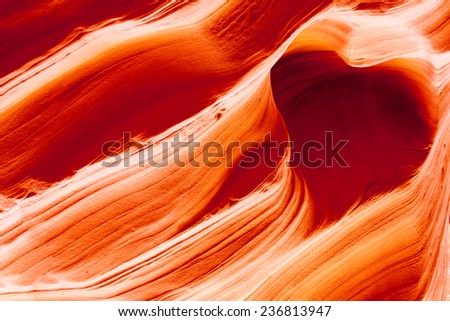 Vibrant orange ancient sandstone eroded over time by water to form a heart shaped cave inside of Canyon X in Page, Arizona.