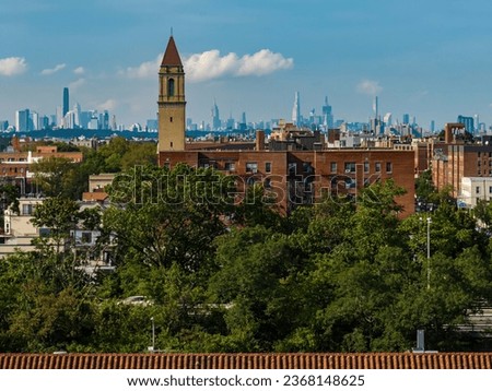 An aerial view of the New York City skyline in the distance on a beautiful day with some clouds, taken with a drone camera. Brighton Beach Brooklyn, a residential neighborhood is in the foreground.