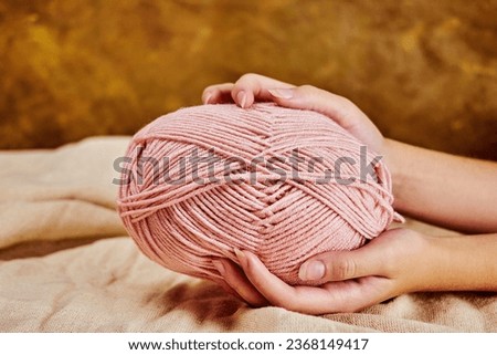 female hands hold an oblong skein of pink yarn for knitting in an atmosphere of creativity and comfort, close-up Royalty-Free Stock Photo #2368149417