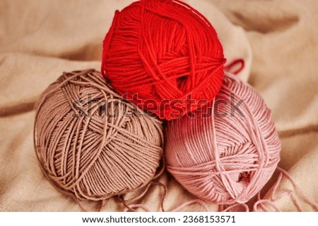 three skeins of beige, pink and red yarn lie on top of each other on natural linen fabric, cozy warm autumn atmosphere Royalty-Free Stock Photo #2368153571