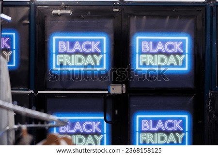 Glowing neon Black Friday sale signs on entrance shopping mall doors, local retail store offering deals and big discounts during seasonal sale, ready to open for shoppers. Clothes shop advertisement