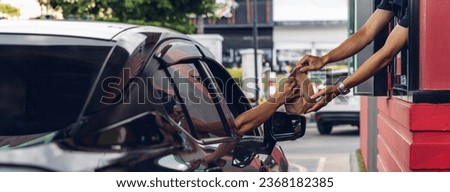 Hand Man in car receiving coffee in drive thru fast food restaurant. Staff serving takeaway order for driver in delivery window. Drive through and takeaway for buy fast food for protect covid19. Royalty-Free Stock Photo #2368182385