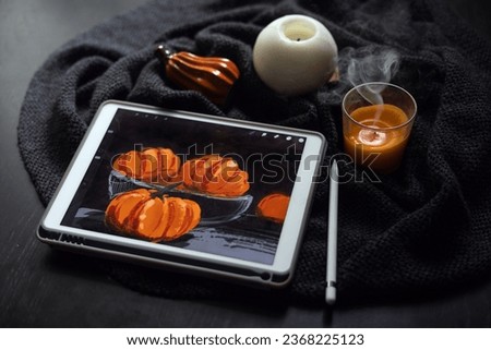 The still life picture with pumpkins drawn on the electronic tablet next to extinguished candle and ceramic pumpkin figurine on black table. The concept of modern art. Halloween, Thanksgiving day
