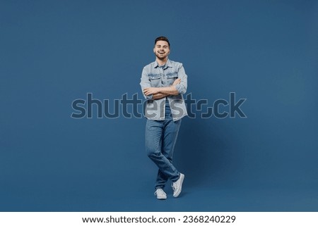 Full size length body laughing beautiful happy handsome young brunet man 20s wears denim jacket hold hands crossed isolated on dark blue background studio portrait. People emotions lifestyle concept. Royalty-Free Stock Photo #2368240229