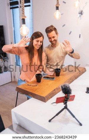 Vertical photo of couple of streamers waving to the camera recording online with a mobile