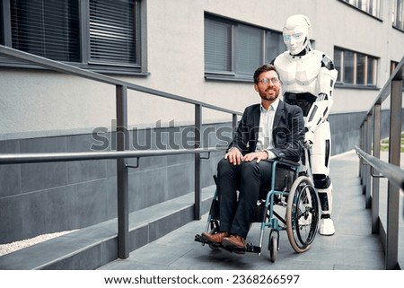 A robot carries a young businessman in a suit along a ramp outside a building in a wheelchair. The future with artificial intelligence.