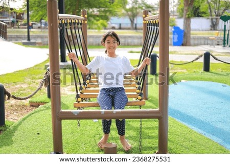 Little kid girl asian  while enjoying on the playground. Which increases the development and enhances outside the classroom learning skills concept.