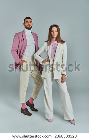 full length of successful business couple in stylish formal wear posing on grey, classic fashion