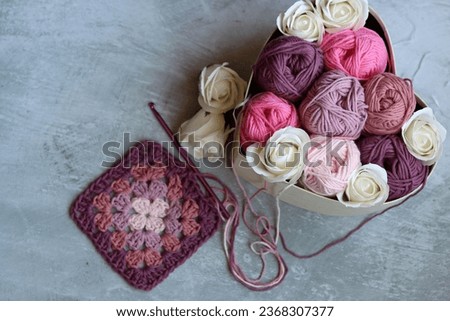 Granny square crochet pattern. Colorful photo of soft pink organic yarn. Hobbies and leisure concept. Light grey background with copy space.
