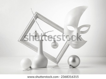 Monochrome still life: mask on a white background, picture frame, abstraction.