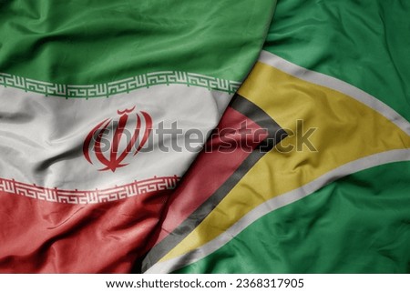 big waving realistic national colorful flag of iran and national flag of guyana . macro