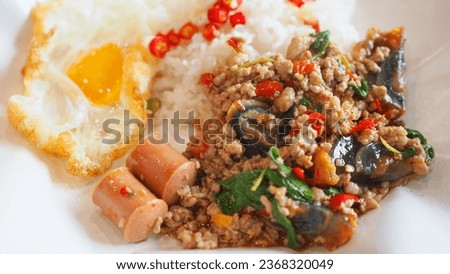 Picture of rice top with stir-fried Century Egg Preserved Egg and Minced Pork with Crispy Basil and fried egg, A popular spicy food among Thai people. The back shows the red chili in fish sauce.