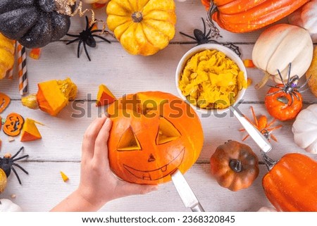 Preparation for Halloween with carving cutting pumpkin Jack Lantern. Female, woman and kids hands in frame, decorate, drawing and carves scary Halloween party Pumpkin top view copy space