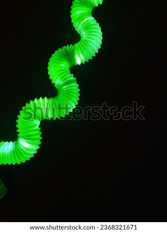 neon green corrugated pipe in the form of wave bends on a black background for graphic design