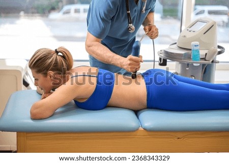 Skilled male therapist performing extracorporeal shock wave therapy Royalty-Free Stock Photo #2368343329