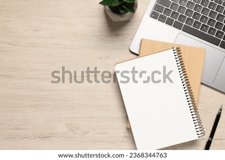 Flat lay composition with laptop and different stationery on light wooden desk, space for text. Home office