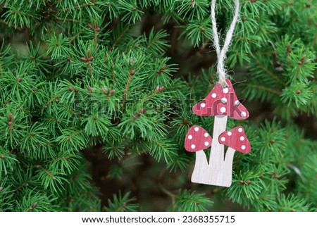 Wooden toy mushrooms on the branches of a Christmas tree. Handmade eco friendly holiday decoration.