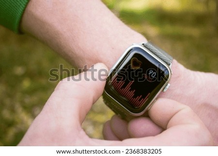 Man using smart watch with heart rate monitor on the screen in the forest