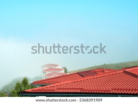Line of rooftop finishes into the clouds. Modern roof made of corrugated red metal tiles roofing. Roofing of buildings with tiles Royalty-Free Stock Photo #2368391909