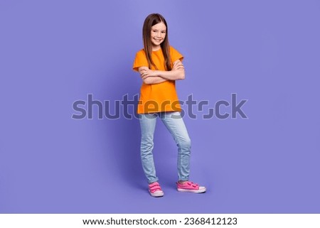 Full size photo of positive schoolgirl wear stylish t-shirt denim trousers standing hold arms folded isolated on violet color background