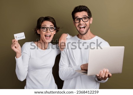 Photo of excited funky married couple wear white shirts spectacles virtual banking modern gadget isolated brown color background