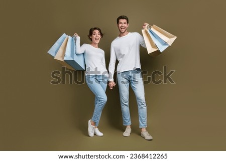 Full length photo of excited funky married couple wear white shirts rising bargains isolated brown color background