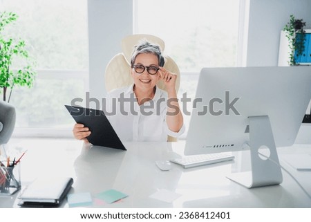 Photo of charming positive lady assistant wear white shirt reading recruitment cv indoors workplace workstation