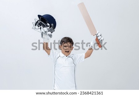 Kid in cricket dress holding bat and Helmet celebrating Century on isolated background Studio shot, cricket concept