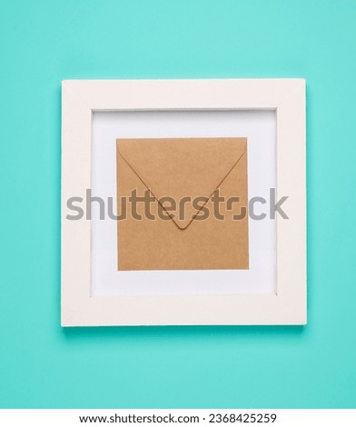 Craft envelope in white square frame, blue background. Aesthetic minimal still life. Concept photo. Top view