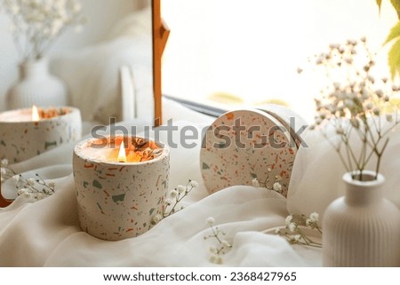 Holder with burning candle, gypsophila flowers and mirror on windowsill in room, closeup Royalty-Free Stock Photo #2368427965