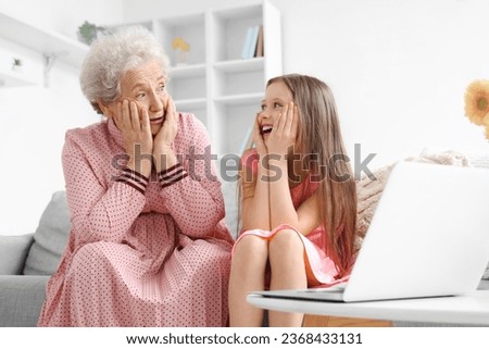 Little girl with her grandmother watching video at home