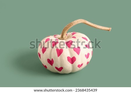 Pumpkin with painted hearts on green background