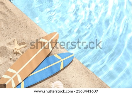 Mini surfboards with starfish and seashell on sand near water