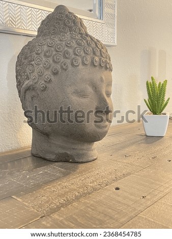 An lonely plant in a pot with copy space next to a Buddha statue in the background of a white background.