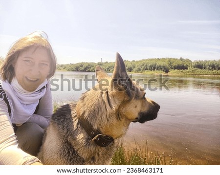 Dog German Shepherd and woman or girl in nature near water in summer, spring or summer sunny day. Russian eastern European dog and mistress, trainer. Veo outside and blue sky background