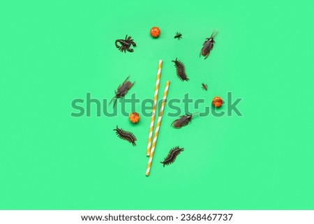 Halloween composition with candy bugs, straws and pumpkins on green background