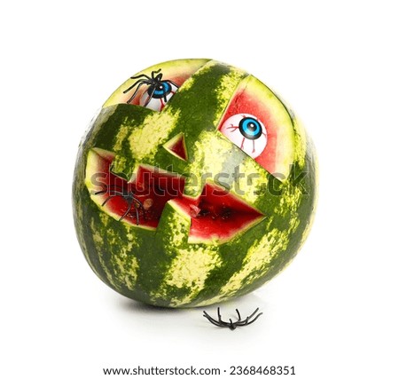 Carved watermelon for Halloween with eyes and spiders on white background