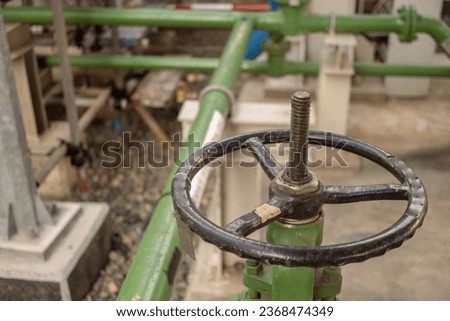 Manual gate valve on the water distribution pipe line on the power plant. The photo is suitable to use for industry background photography, power plant poster and electricity content media.