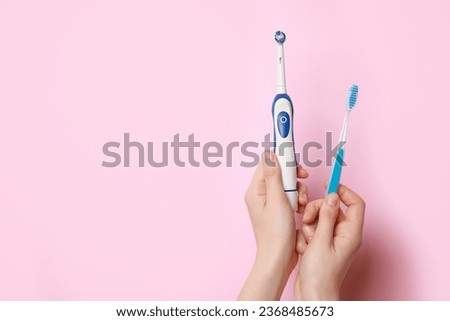 Woman holding electric and plastic toothbrushes on pink background, closeup. Space for text