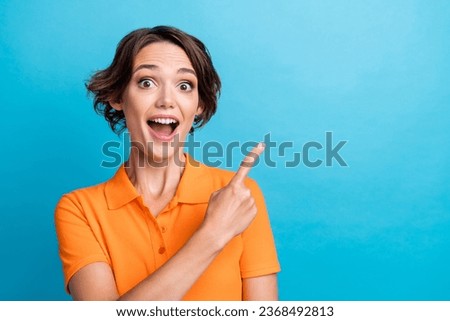 Photo of good mood impressed girl dressed orange polo open mouth pointing finger empty space isolated blue color background
