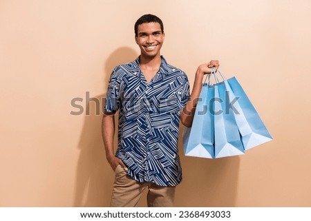 Photo of good mood cute guy dressed print shirt smiling rising bargains isolated beige color background