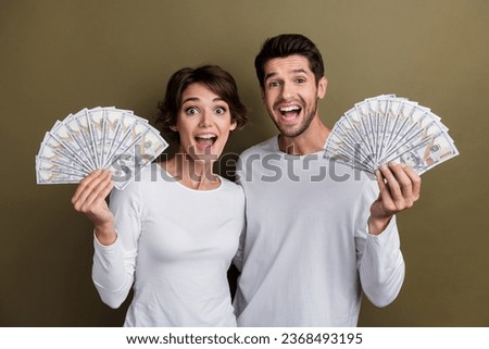 Photo of pretty excited married couple wear white shirts showing money fans isolated brown color background