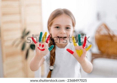 The child draws at home. Paint on the hands. Decorative and applied art for children. A little girl draws a bright picture. A creative child plays and learns.