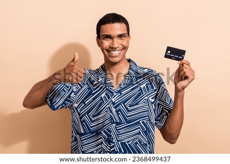 Photo of satisfied man stylish clothes hand hold bank card recommend nfc cashless payment thumb up isolated on beige color background