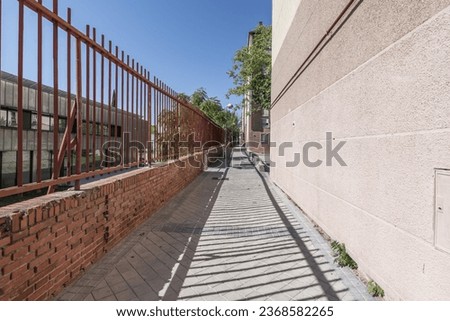 A long narrow road along it with a red metal fence on one side Royalty-Free Stock Photo #2368582265