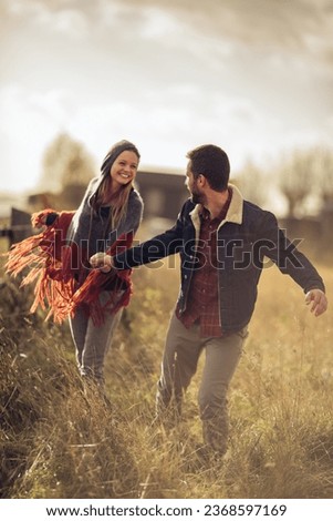 Young couple having a stroll on a grassland in the countryside Royalty-Free Stock Photo #2368597169